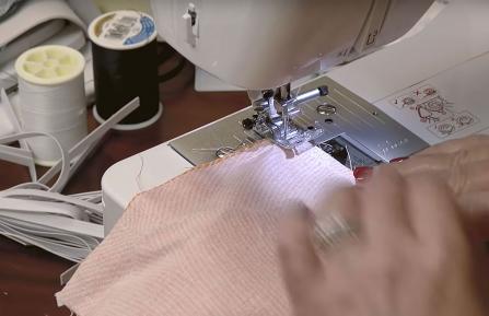 A person's hands guiding fabric through a sewing machine