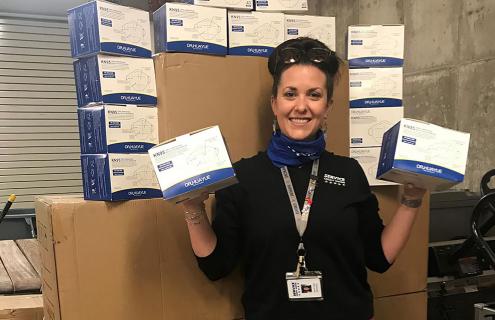 Service Credit Union employee holding boxes of KN95 masks