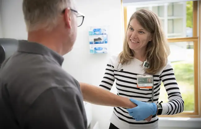 A female healthcare provider treating an older male patient in an examination room