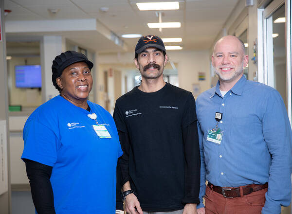 3 staff members from different departments standing together in hallway