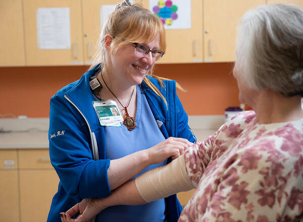 nurse wrapping bandage on patients arm