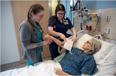 2 nurses caring for patient. one nurse is taking patients blood pressure
